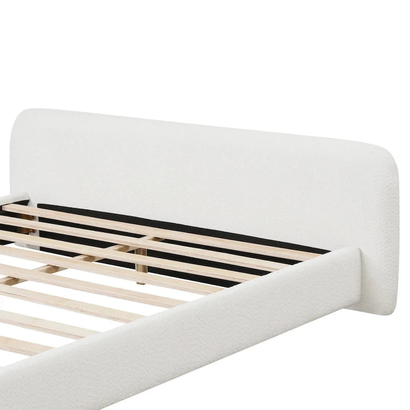 Lit plateforme en boucle blanche capitonnée, cadre de lit bas avec sommier à lattes en bois et pieds centraux en bois.